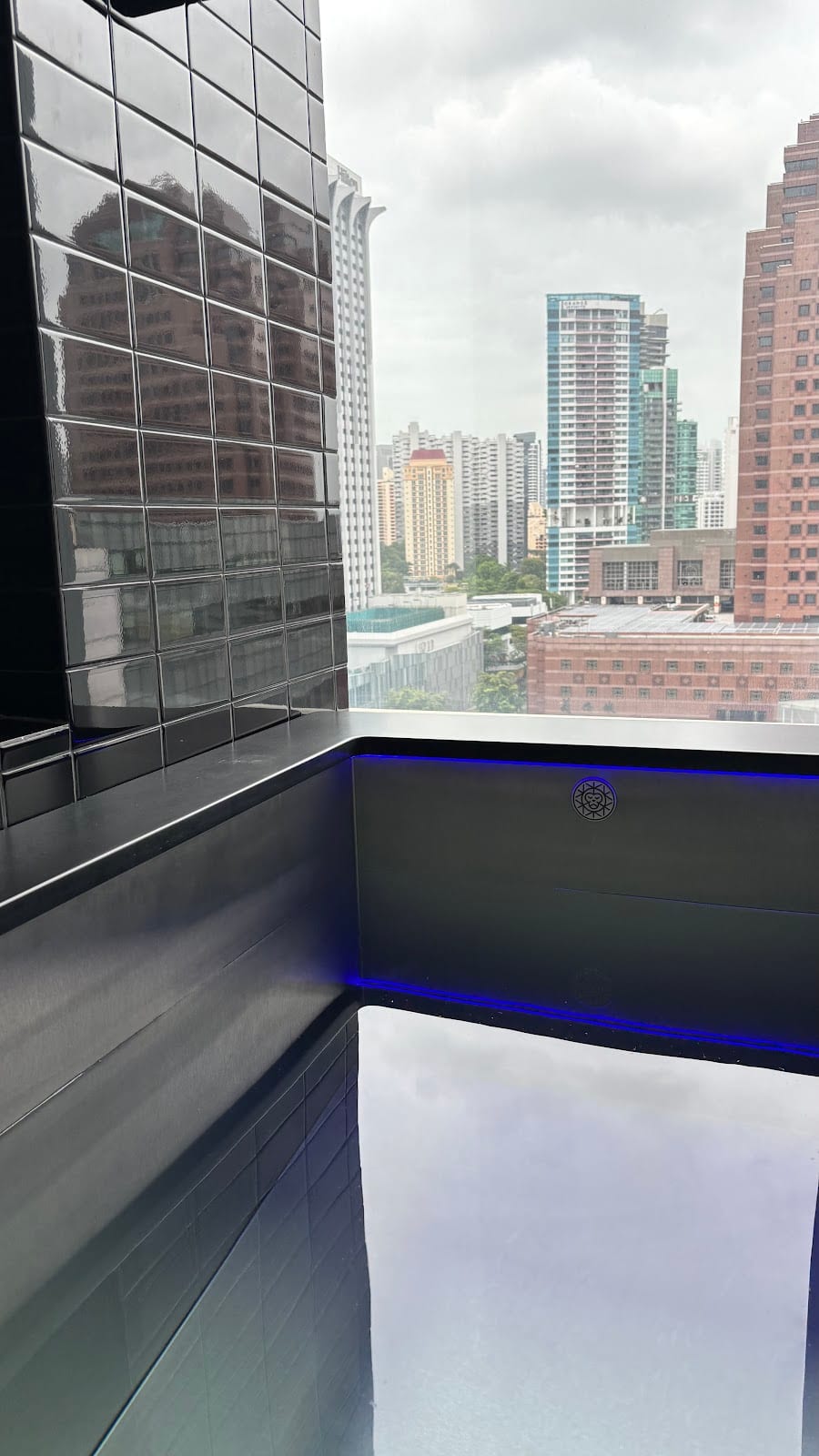 The cold plunge pool at Asia Longevity, lit in blue, with a view over Orchard Road
